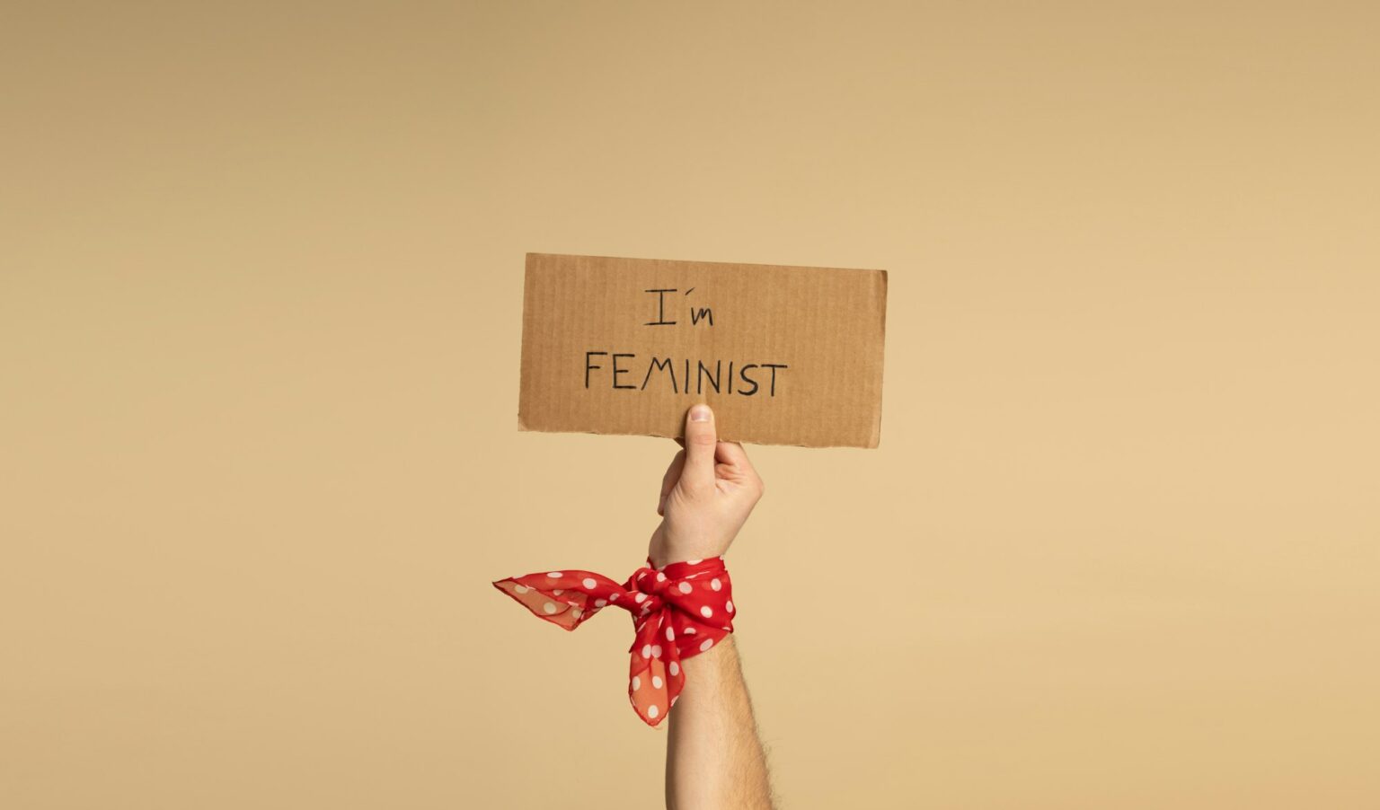 A hand of a man holding a sign saying "I am feminist".