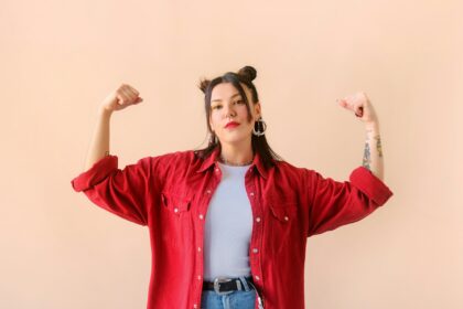 Strong powerful stylish woman with tattoo, raises arms