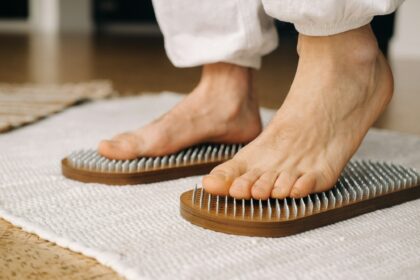 The man's feet are next to boards with nails. Yoga classes