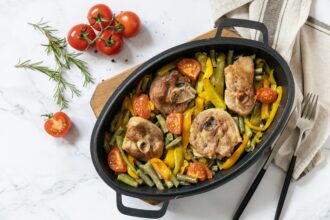 Baked turkey meat steaks with spices and vegetables on a marble tabletop.