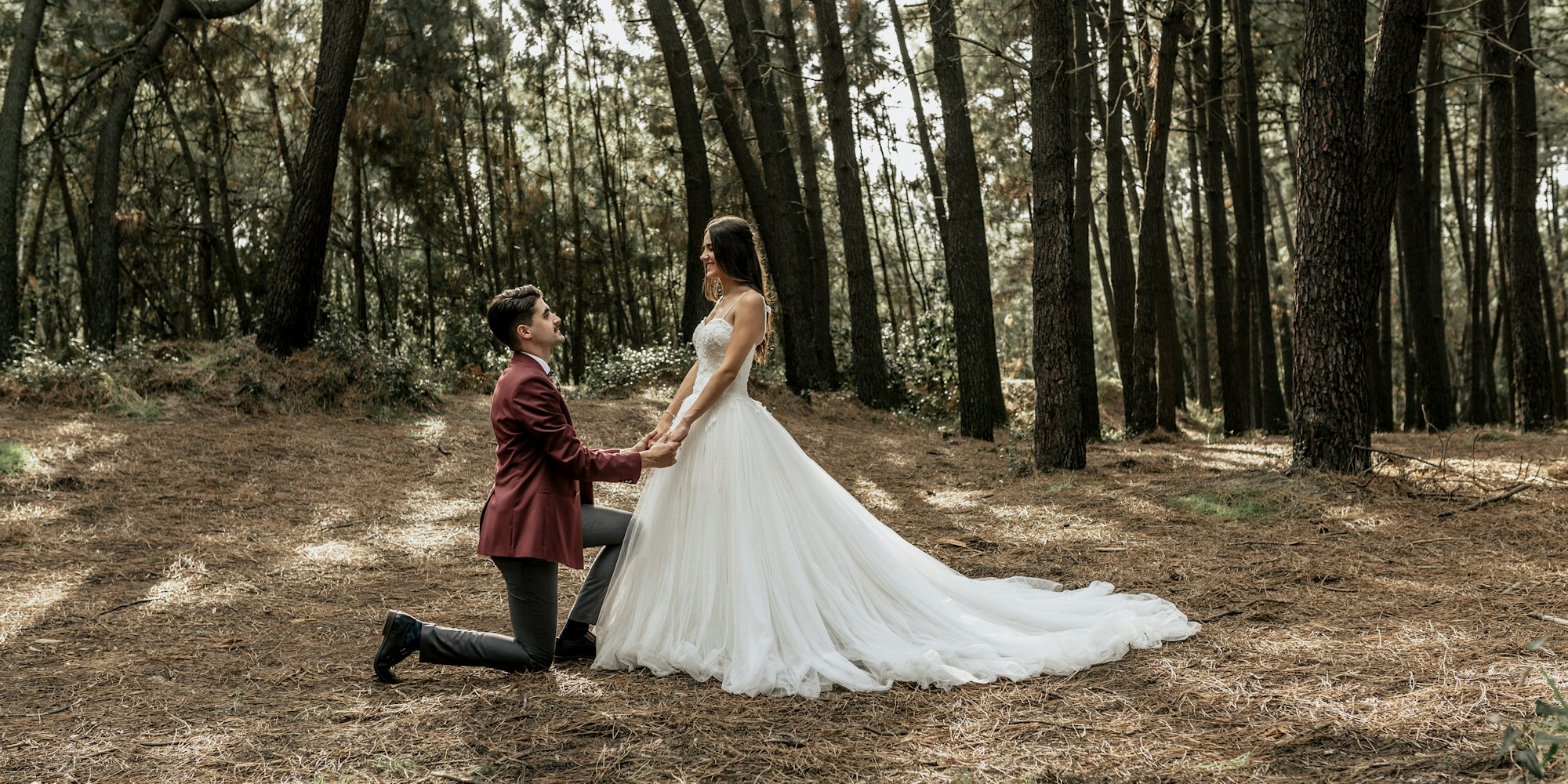 Man kneeling making a marriage proposal to happy bride in forest